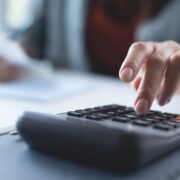Doing finance, budgeting and tax calculation. Close up woman hand using calculator to calculate home finance, accounting with laptop computer on table, budget management, monthly expenses
