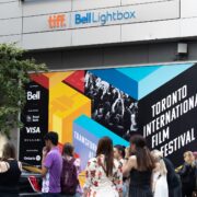 Toronto, ON, Canada - September 9, 2022: A crowd outside of the main celebrity entrance at TIFF, the Toronto International Film Festival, next to a colourful poster in the background.