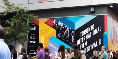 Toronto, ON, Canada - September 9, 2022: A crowd outside of the main celebrity entrance at TIFF, the Toronto International Film Festival, next to a colourful poster in the background.