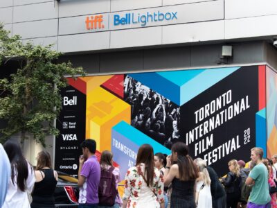 Toronto, ON, Canada - September 9, 2022: A crowd outside of the main celebrity entrance at TIFF, the Toronto International Film Festival, next to a colourful poster in the background.