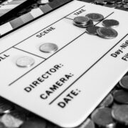 Clapperboard with coins above and on it creating a relation between filmmaking and business [Black and White version]