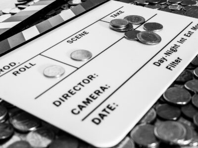 Clapperboard with coins above and on it creating a relation between filmmaking and business [Black and White version]
