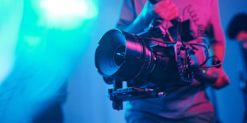 Close-up of young cameraman shooting with professional camera while making content in studio