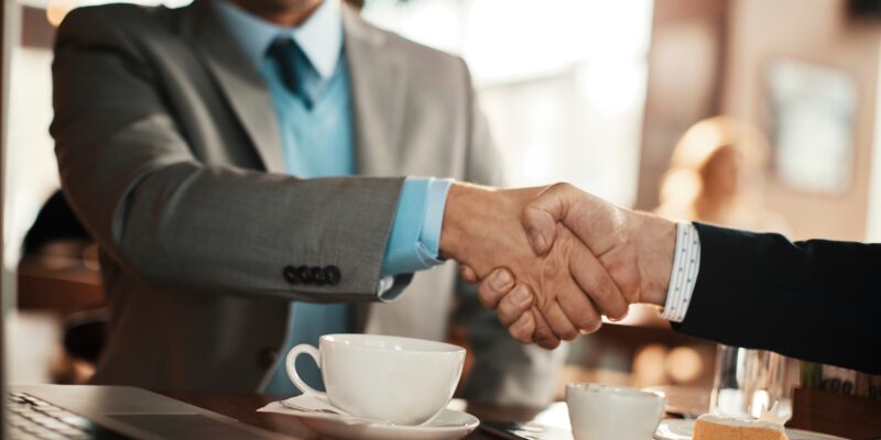 Young businessman reaching an agreement with a colleague over some coffee in a cafe