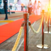 Wide panoramic view rope fencing with gold pillars with a red carpet for celebrities and guests of an expensive event with crowds of people