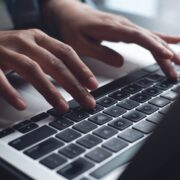 Close up of business woman hands typing on laptop computer and digital tablet, searching and surfing the internet on office desk, online working, telecommuting, freelancer at work concept