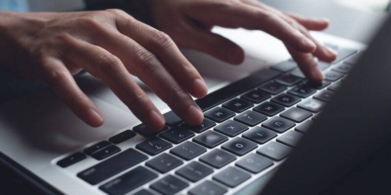 Close up of business woman hands typing on laptop computer and digital tablet, searching and surfing the internet on office desk, online working, telecommuting, freelancer at work concept