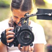 Cute girl walking in the forest and shooting a video using a professional video camera
