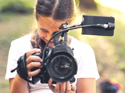 Cute girl walking in the forest and shooting a video using a professional video camera