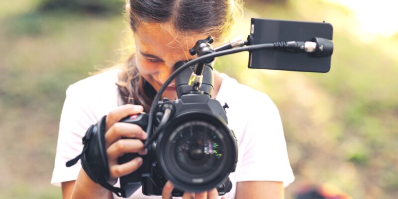 Cute girl walking in the forest and shooting a video using a professional video camera
