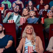 A young adult mother and father are in a movie theater with their small child enjoying a movie together over the weekend.