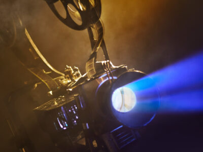 Old movie projector with the film on the brick wall background